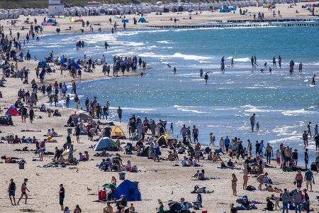 Urlauber und Tagesgäste nutzen das sonnige warme Wetter zu einem Strandbesuch an der Ostseeküste in Warnemünde.