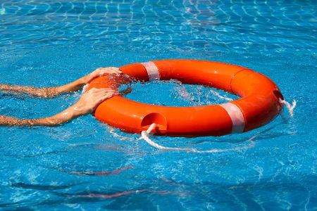 Hände halten sich am im Wasser treibenden Rettungsring fest