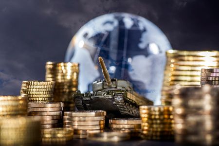 Geldstapel und ein Panzer vor einem Globus, der globale Rüstung und Finanzen symbolisiert Geldstapel und ein Panzer vor einem Globus, der globale Rüstung und Finanzen symbolisiert